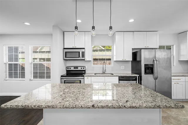 a kitchen with granite countertop a refrigerator stove and microwave