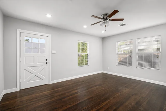 a view of an empty room with wooden floor and a window