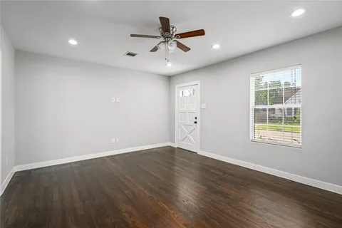 an empty room with wooden floor and windows