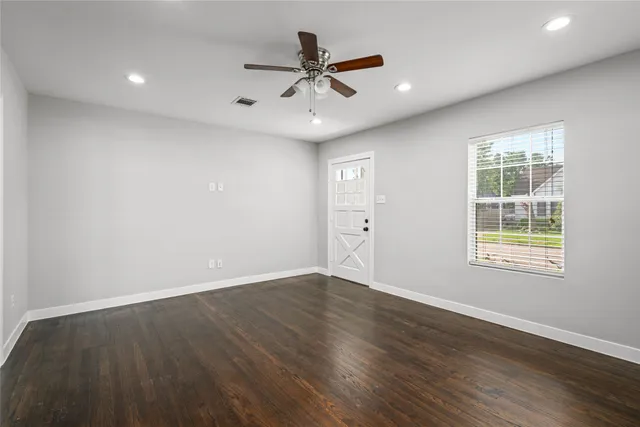 an empty room with wooden floor and windows