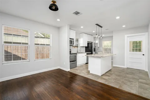 a view of an empty room with wooden floor and a ceiling fan