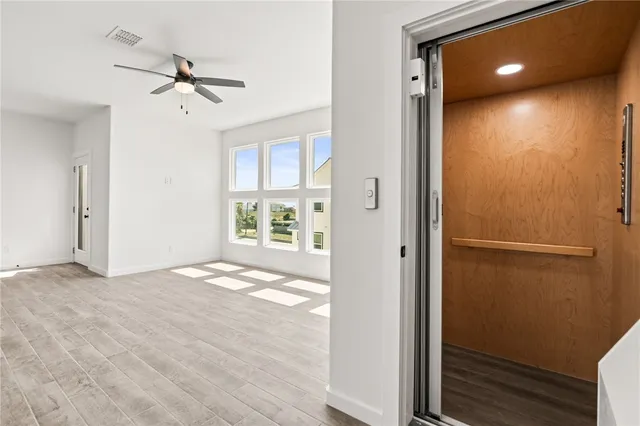 a view of empty room with wooden floor and fan