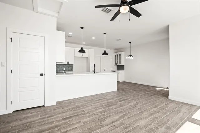 a view of kitchen and empty room with wooden floor