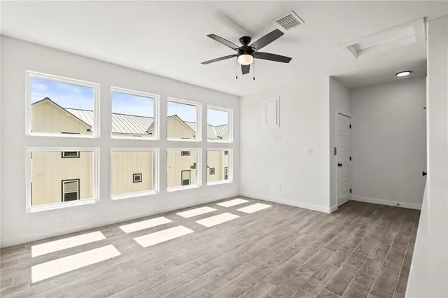 a view of an empty room with a window and wooden floor