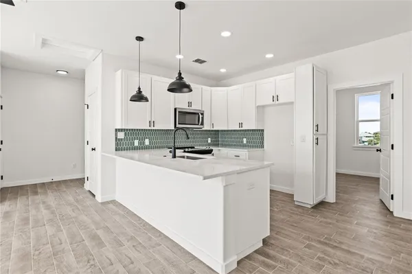 a large kitchen with stainless steel appliances kitchen island wooden cabinets a refrigerator a sink and a stove