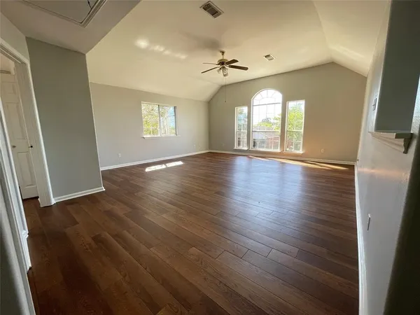a view of empty room with wooden floor and fan