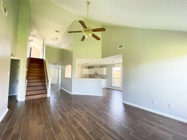 an empty room with wooden floor fireplace and windows