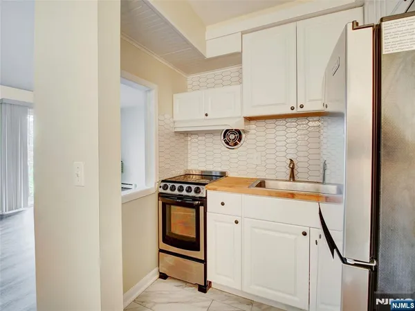 a view of cabinets a sink and a stove in a white cabinet