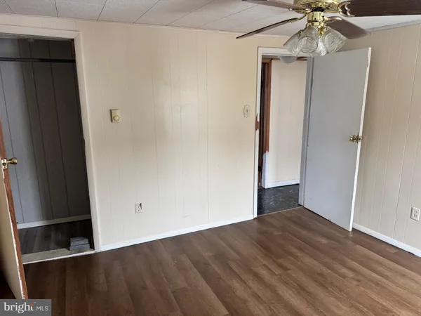an empty room with wooden floor fan and windows