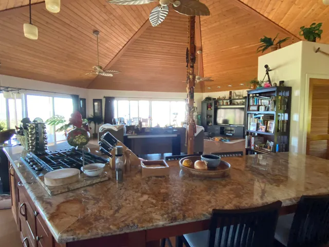 a view of a dining room with furniture one side kitchen view and wooden floor