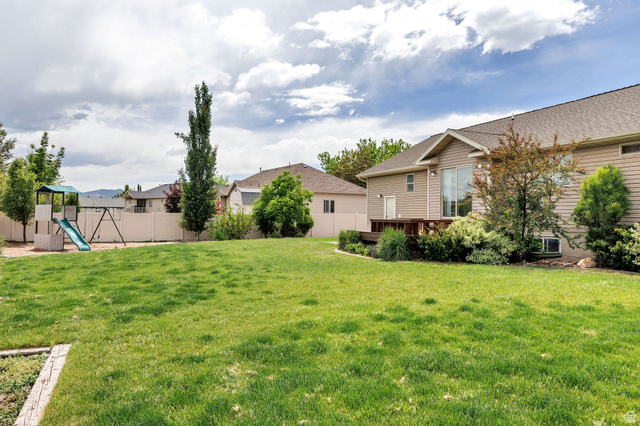 2912 South 1080th Street West Logan, UT 84321 - Photo 41 of 43 Expansive backyard featuring a manicured lawn, a wooden deck, mature trees, and a privacy fence