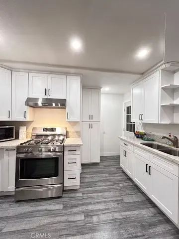 a kitchen with stainless steel appliances a stove and white cabinets
