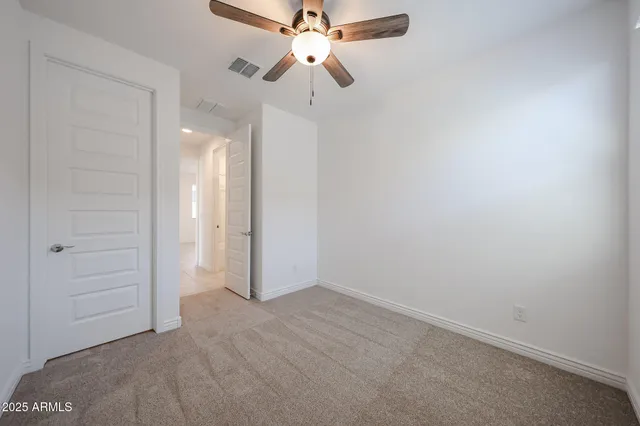 an empty room with closet and a chandelier fan