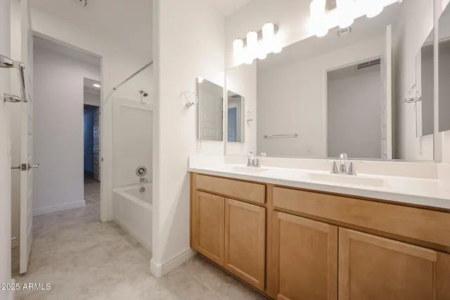 a bathroom with a double vanity sink mirror and bathtub