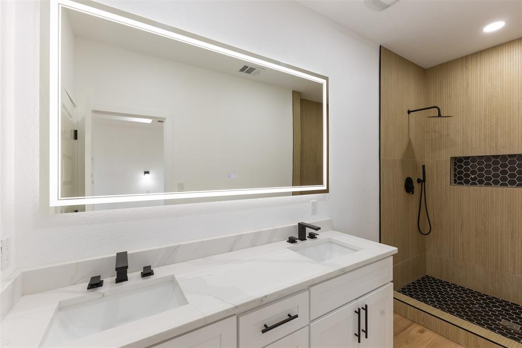 3526 Spring Avenue Dallas, TX 75210 - Photo 17 of 27 Full bathroom featuring double vanity, a tile shower, and light wood-type flooring