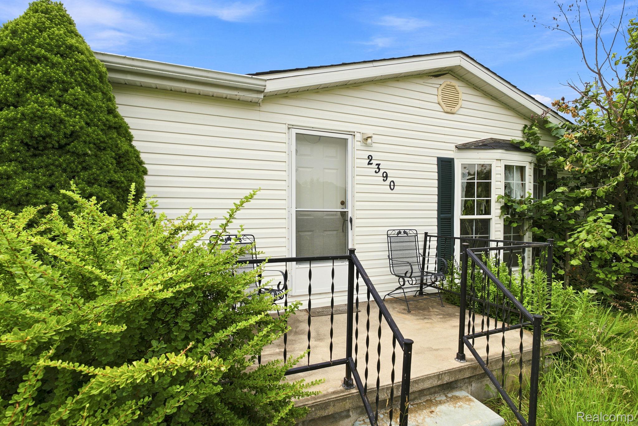 White siding exterior with a bay window, front entry door, and concrete porch