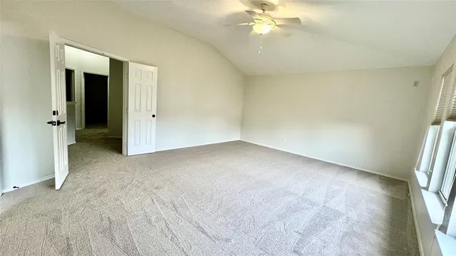 an empty room with a chandelier fan and windows