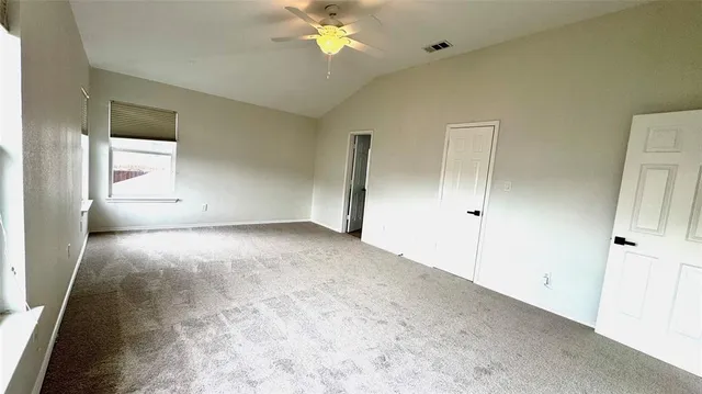 an empty room with chandelier fan and windows