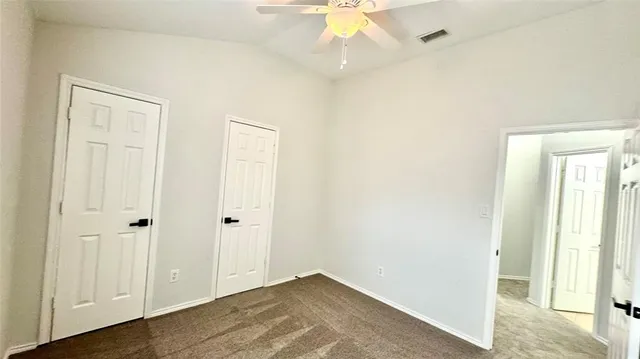 an empty room with a ceiling fan and wooden floor