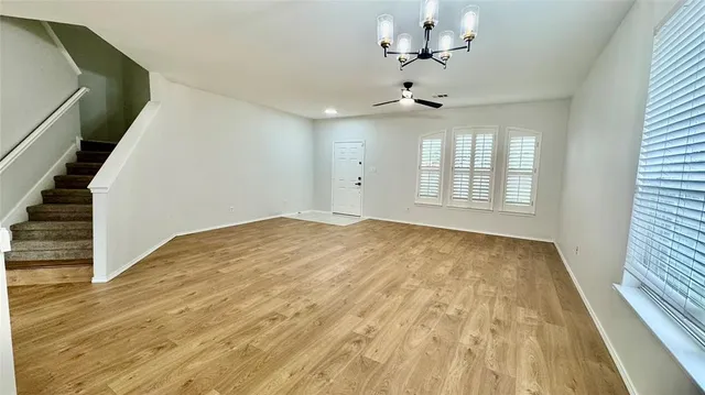 a view of an empty room with wooden floor and fan
