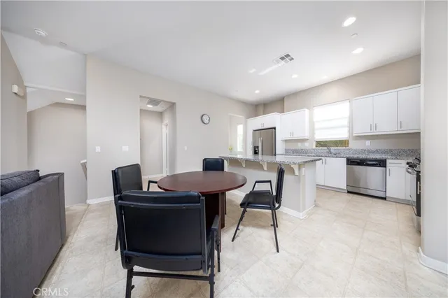 a open dining room with kitchen island furniture a sink a kitchen island and stainless steel appliances