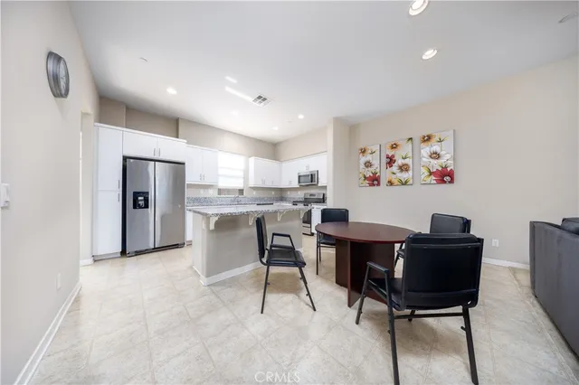 a view of kitchen with refrigerator stove dining table and chairs