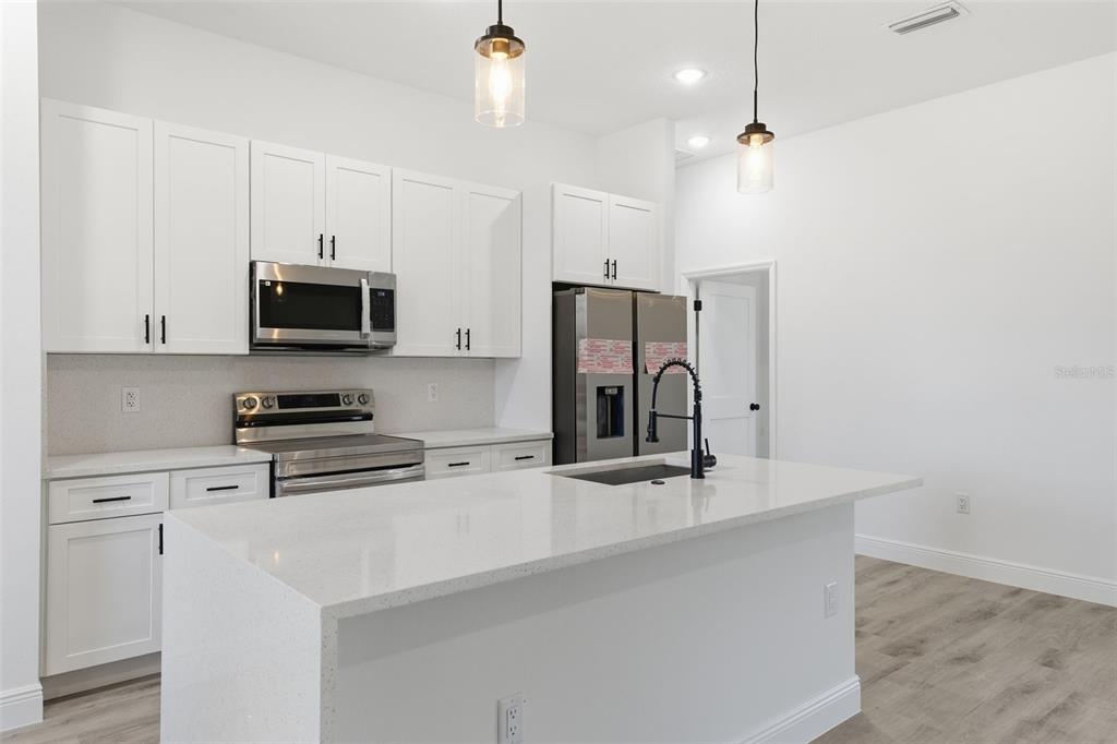 4473 Southwest 168th Lane Ocala, FL 34473 - Photo 11 of 33 a kitchen with stainless steel appliances a sink a stove a microwave a refrigerator a sink and white cabinets