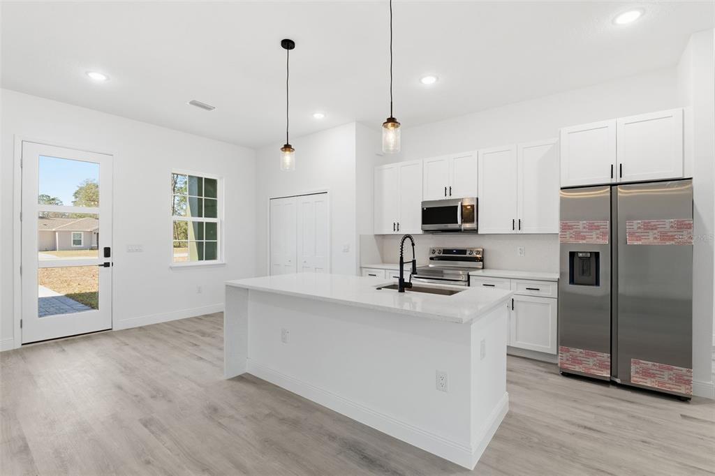 4473 Southwest 168th Lane Ocala, FL 34473 - Photo 9 of 33 a kitchen with stainless steel appliances granite countertop a refrigerator a stove a microwave oven a sink with island and chairs
