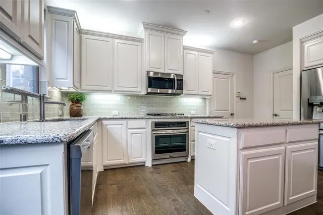 a kitchen with granite countertop cabinets stainless steel appliances and a sink