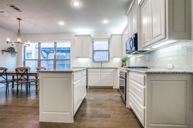 a kitchen with white cabinets and sink