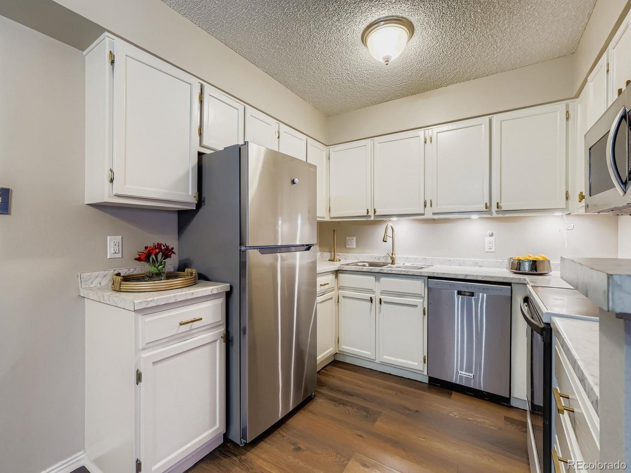 10251 West 44th Avenue, Unit 106 Wheat Ridge, CO 80033 - Photo 4 of 17 a kitchen with stainless steel appliances granite countertop a refrigerator sink and cabinets