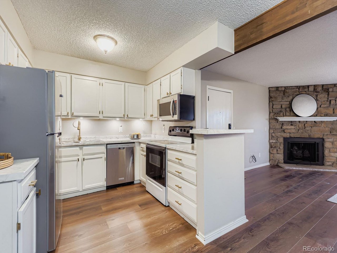 10251 West 44th Avenue, Unit 106 Wheat Ridge, CO 80033 - Photo 5 of 17 a kitchen with granite countertop a stove top oven sink and cabinets