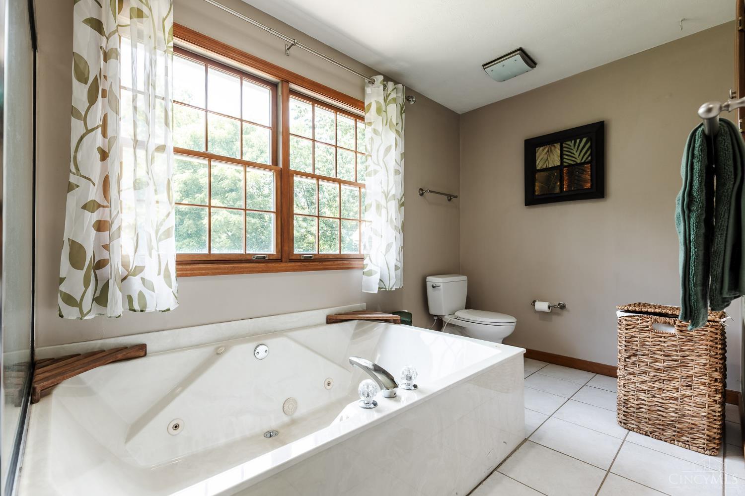 623 Ibold Road Loveland, OH 45140 - Photo 20 of 35 Completing the primary suite is a spacious ensuite bath featuring a double vanity, walk-in shower, relaxing jetted tub, and large window overlooking the backyard, creating a bright and inviting retreat.