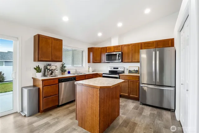 a kitchen with stainless steel appliances granite countertop a refrigerator stove a sink dishwasher and a refrigerator with wooden floor