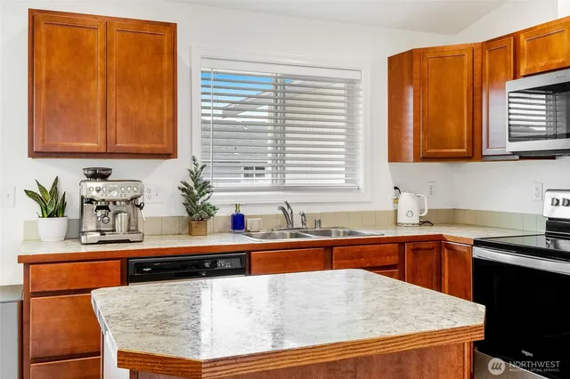 a kitchen with stainless steel appliances granite countertop wooden cabinets a sink and a window