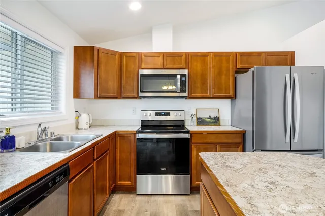 a kitchen with stainless steel appliances granite countertop a stove a sink and a refrigerator
