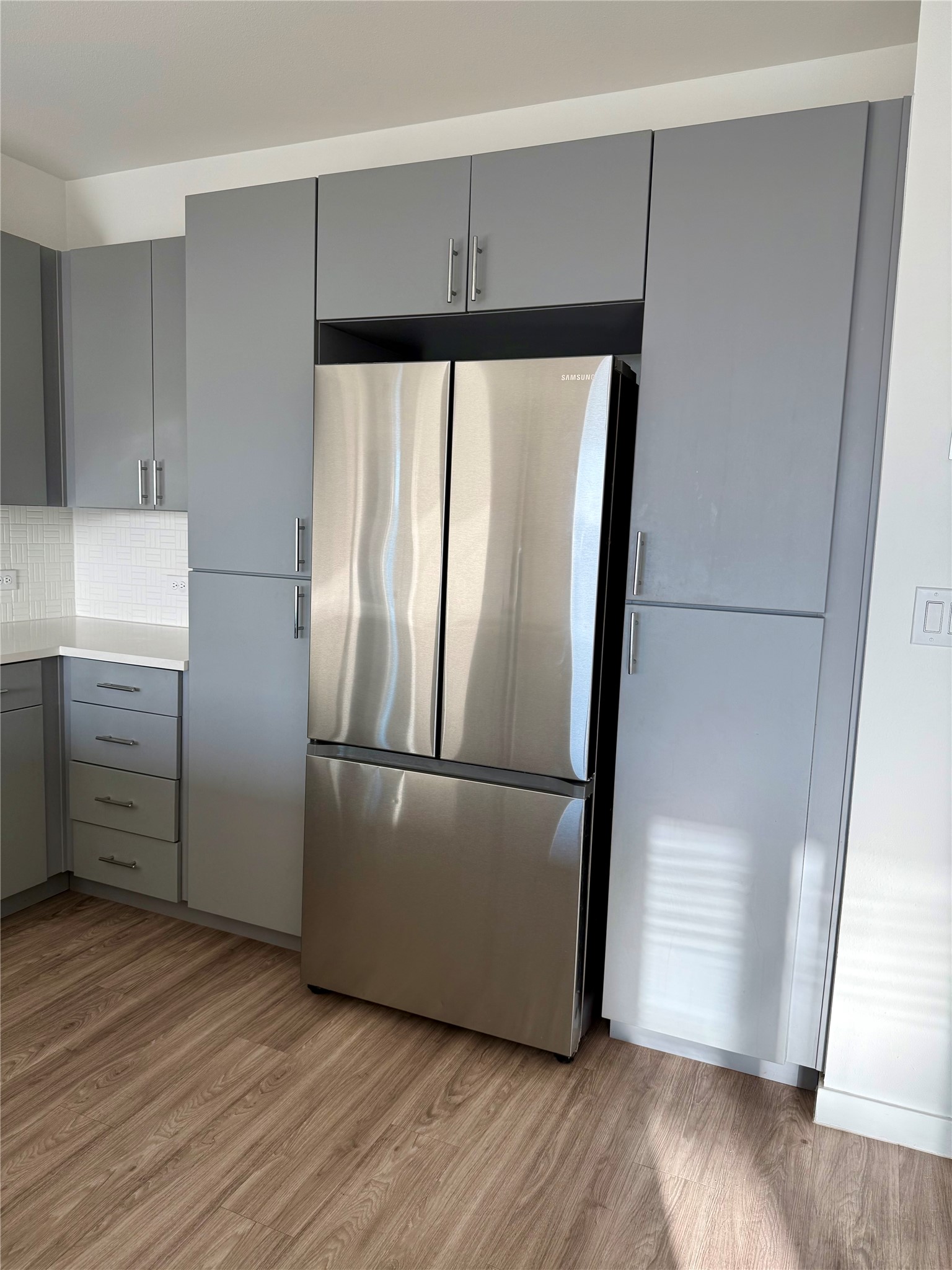 Sleek contemporary cabinetry seamlessly integrates modern appliances above warm wood floors.