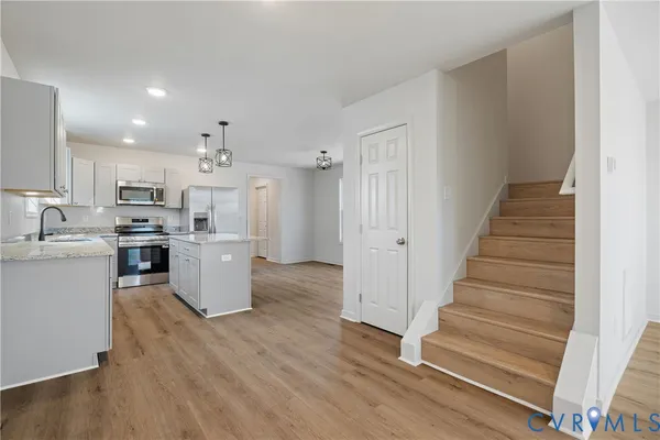 a living room with wooden floors and kitchen view
