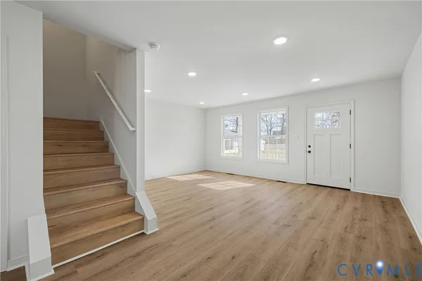 a view of an empty room with wooden floor and stairs