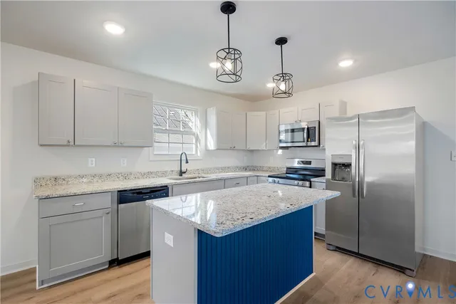 a kitchen with stainless steel appliances granite countertop a sink stove a refrigerator and cabinets with wooden floor