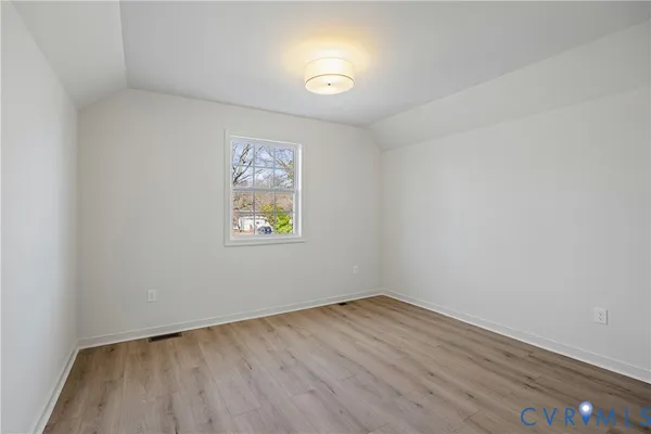an empty room with a window and wooden floor