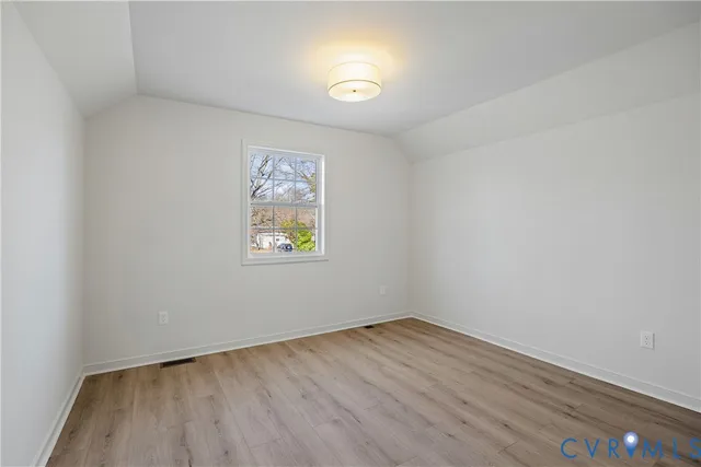 an empty room with a window and wooden floor