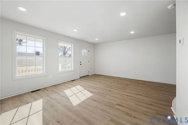an empty room with wooden floor and windows