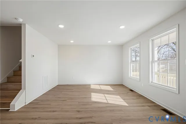 a view of an empty room with wooden floor and a window