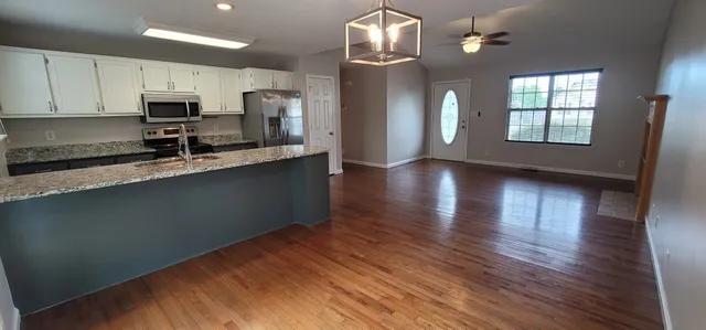 a kitchen with stainless steel appliances granite countertop a refrigerator a stove top oven a sink dishwasher and wooden floor