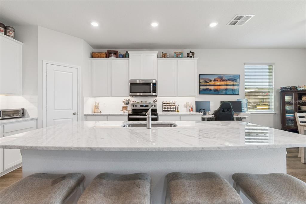 11965 Muskegon Court Parrish, FL 34219 - Photo 17 of 74 a kitchen with stainless steel appliances a stove a sink a microwave a refrigerator and cabinets