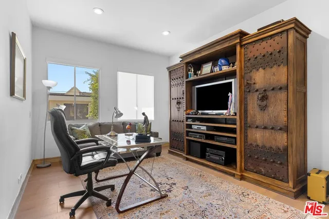 a living room with furniture a flat screen tv and a refrigerator