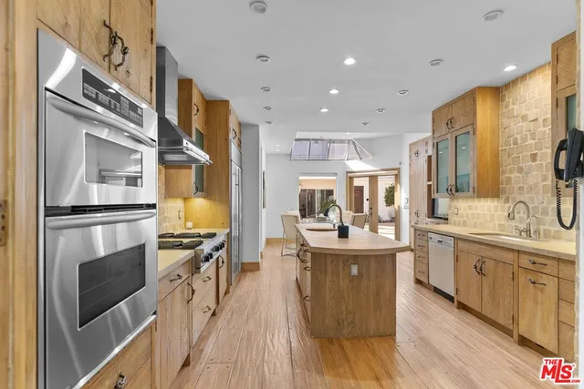 a kitchen with stainless steel appliances granite countertop a refrigerator a stove oven and white cabinets with wooden floors