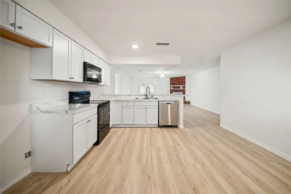 a kitchen with stainless steel appliances granite countertop a stove top oven a sink dishwasher and a microwave with wooden floor