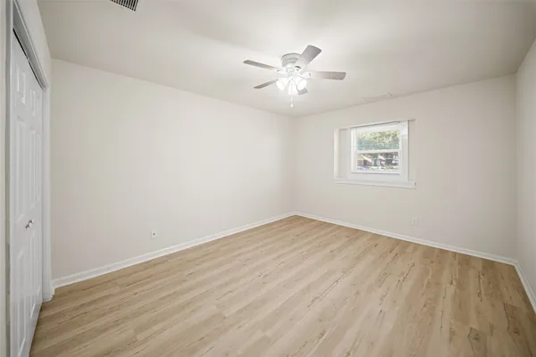 a view of an empty room with chandelier fan and wooden floor